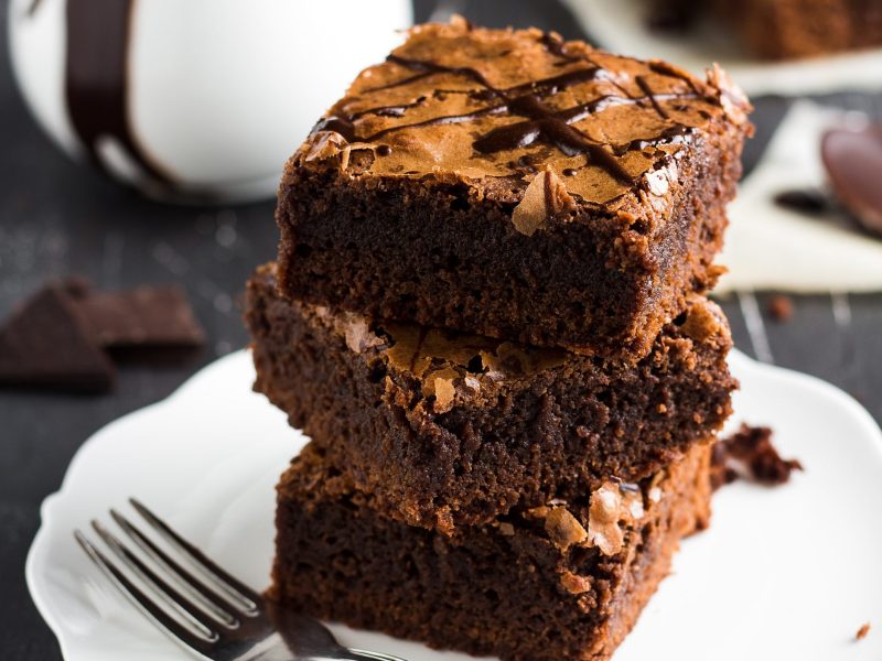 Chocolate brownie cake piece stack on plate homemade pastries sweet cooking with melted chocolate on dark background